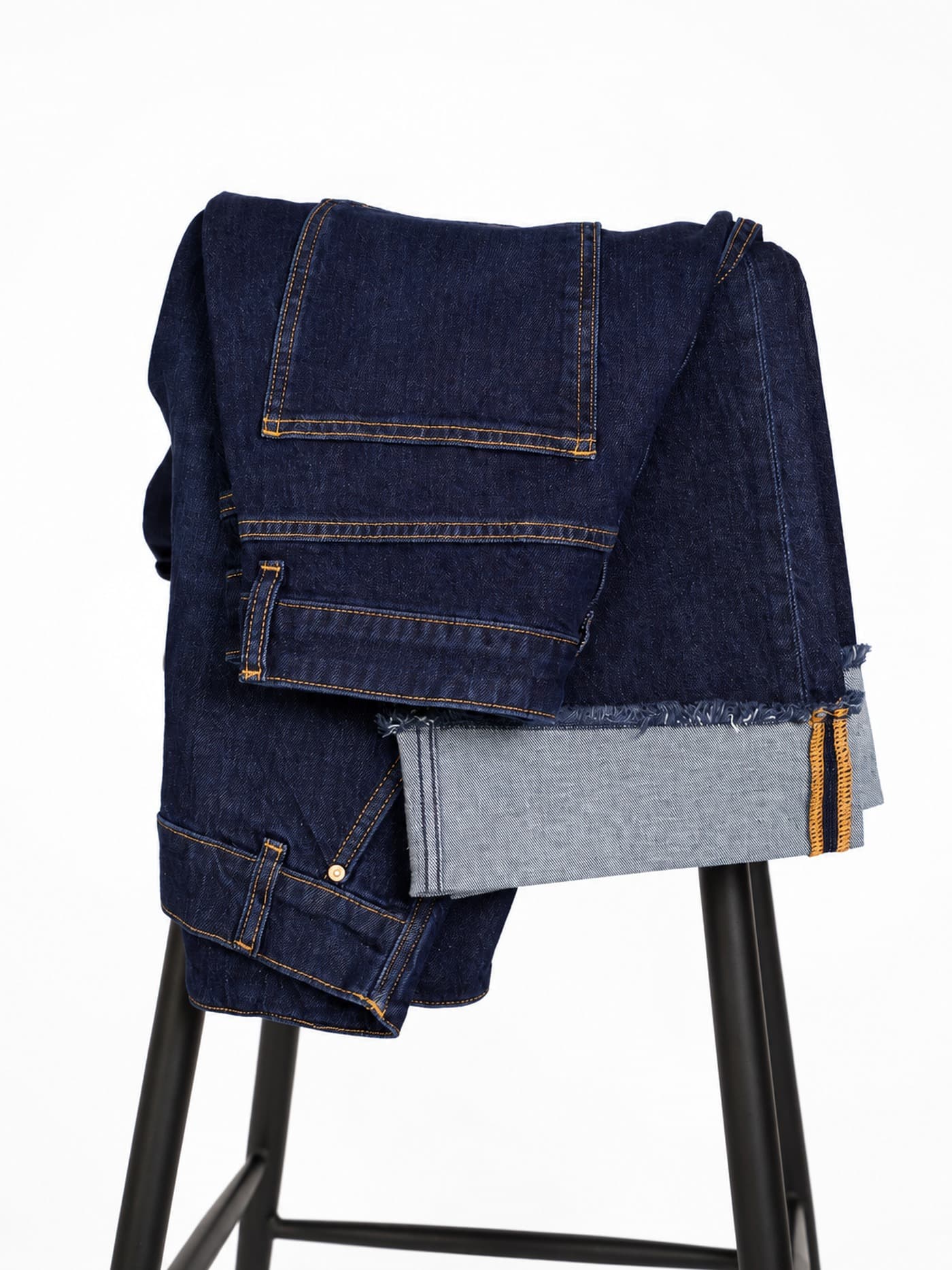 folded jeans with leather brand patch and raw hem